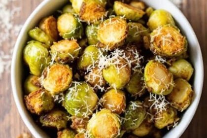 Crispy and Flavorful Air Fried Brussels Sprouts 1 Crispy air fried Brussels sprouts garnished with Parmesan cheese in a rustic bowl on a wooden table.