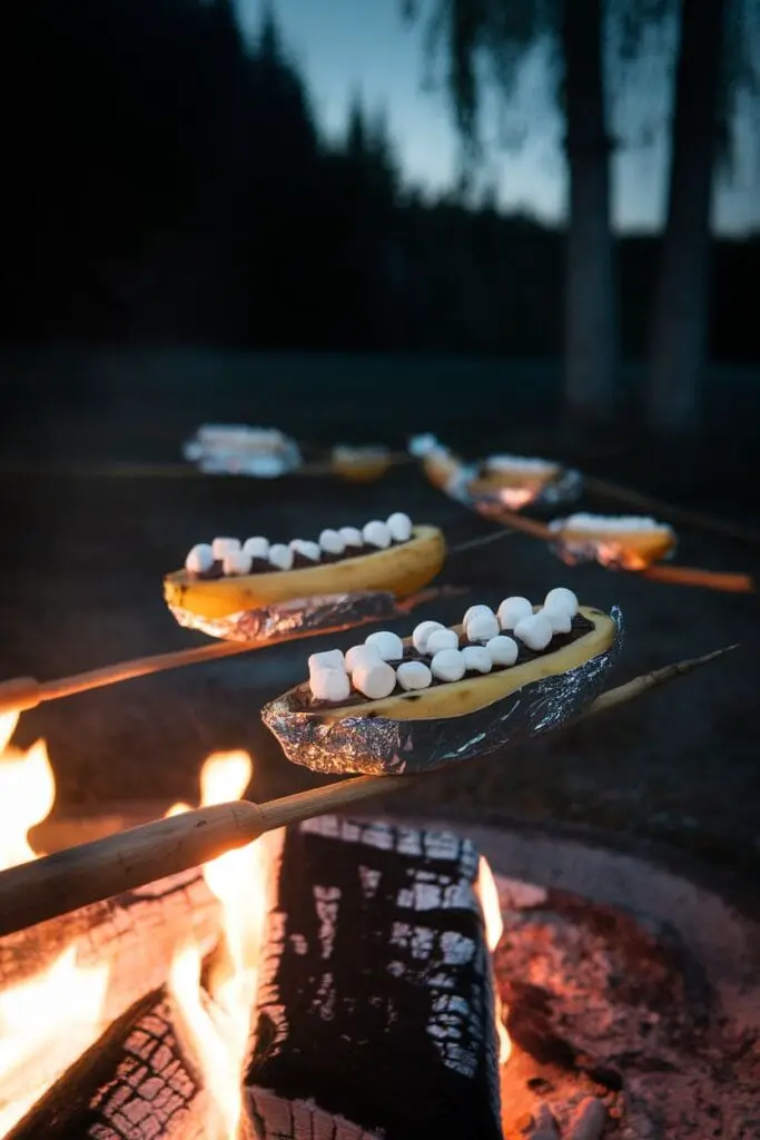 12 Quick and Easy Dinners for Your Next Camping Trip 3 S'mores stuffed banana boats cooking over a campfire