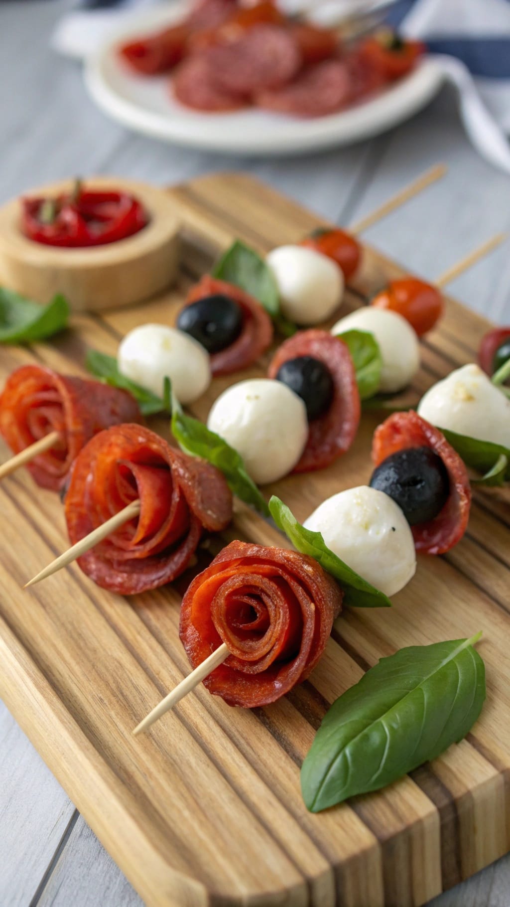 15 Fancy-Looking Christmas Party Foods That Are Secretly Easy 8 A wooden platter with festive antipasto skewers featuring salami, mozzarella, olives, and basil.