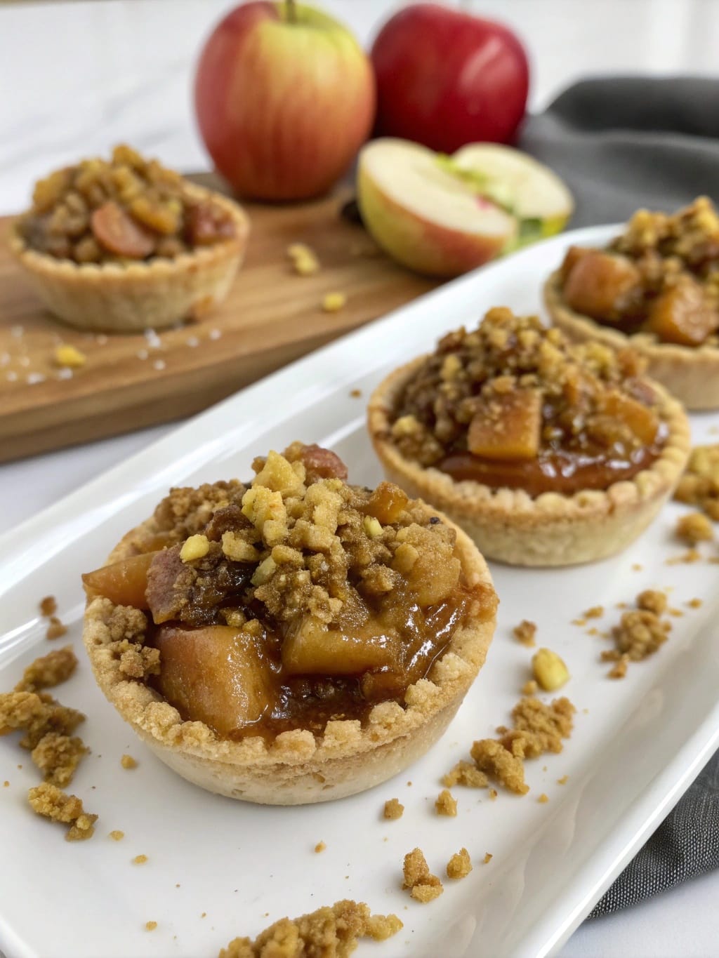 10 Fancy-Looking Desserts That Are Way Easier Than They Look 5 Salted Caramel Apple Pie Minis on a plate with apples in the background.